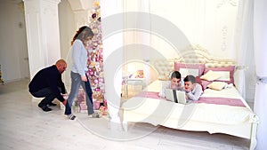 Parents make unexpected surprise for children and spend time together with sons in beautiful bedroom with Christmas tree