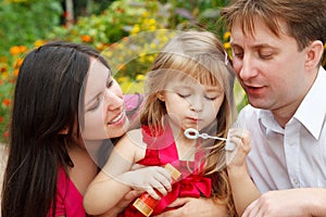 Parents observe as daughter blows soap bubble photo