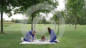 Parents open the blanket for a picnic in the park.