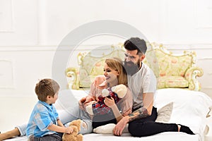 Parents pay attention to kid. Mother and father cuddling while listening their cute little son. Happy family concept