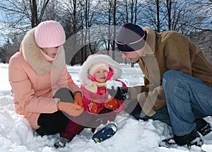 Parents play with the child in winter park