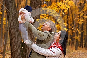 Parents play with little daughter in autumn park