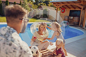 Parents playing with children by the swimming pool