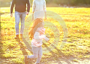 Parents playing with daughter in park at sunset