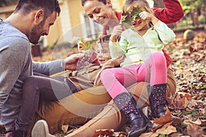 Parents playing with little girls, sitting on ground. Autumn sea