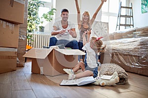 Parents playing with their daughter in new apartment, while unpacking.  new apartment, new beginning, excitement  concept