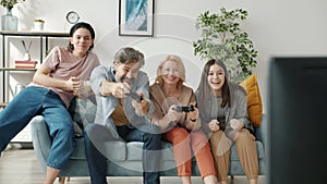 Parents playing video game while teenage children cheering having fun at home