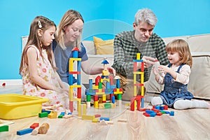 Parents playing wit children with blocks indoors