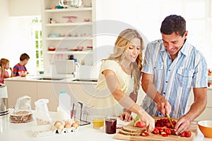 Parents Preparing Family Breakfast In Kitchen