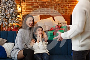 Parents presenting gift box to cute son. Christmas kids, child, portrait. Happy family spending Christmas morning