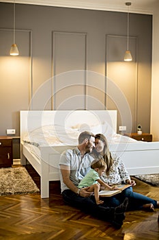 Parents reading book to little boy and have fun on the floor in