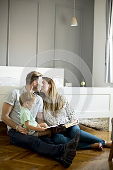 Parents reading book to little boy and have fun on the floot in