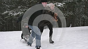 Parents running with their child on a sled in the winter park