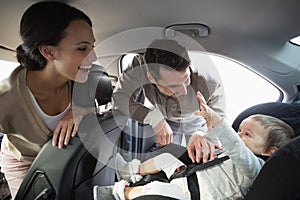 Parents securing baby in the car seat