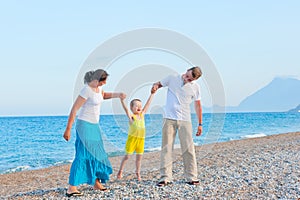 Parents shake their little son on the beach