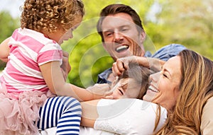 Parents Sitting With Children In Field