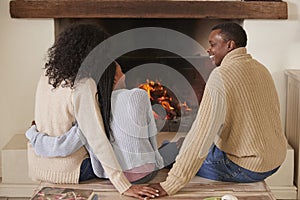 Parents Sitting With Daughter In Lounge Next To Open Fire