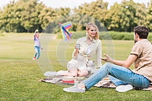parents sitting in plaid at picnic while daughter lying behind