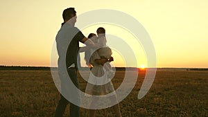 Parents with a small child play outside the city at sunset. Mom dad and kid laugh together. Weekends with family