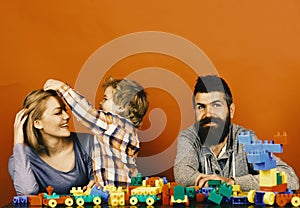 Parents and son with happy faces make brick constructions. Love and family games. Young family spends time in playroom