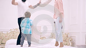 Parents and son having fun with pillows on bed. Family spending free time at home. Happy family jumping on bed together