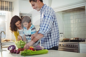 Parents and son preparing salad in the kitchen