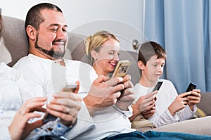 Parents and son using phones at home