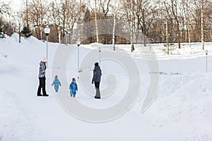 Parents with sons twins walk in winter Park on a Sunny day