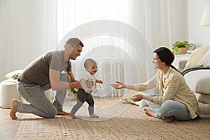 Parents supporting their baby daughter while she learning to walk at home