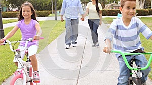 Parents Taking Children To Ride Bikes In Park