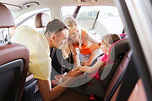 Parents talking to little girl in baby car seat