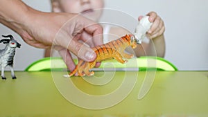 Parents teach a small child to distinguish between animals, a child`s play with toys and parents, close-up, caucasian