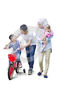 Parents teach their son to ride bicycle