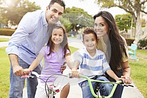 Parents Teaching Children To Ride Bikes In Park