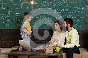 Parents teaching kid at home. Boy presenting his knowledge to mom and dad. Parents listening their son, chalkboard on