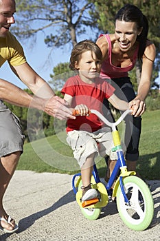 Parents Teaching Son To Ride Bike In Park