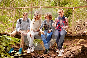 Parents and teens playing, sitting on a bridge in a forest