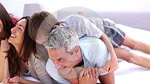 Parents and their children playing on the bed