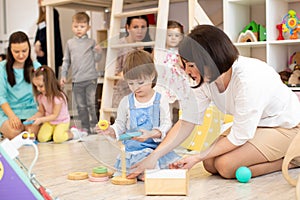 Parents with children playing in playroom in daycare photo