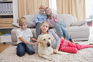 Parents and their children on sofa with labrador