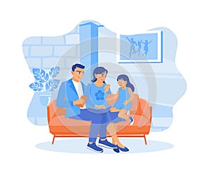 The parents and their little daughter are sitting together on the living room sofa.