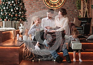 Parents with their young children sitting in the living room decorated for Christmas