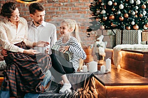 Parents with their young children sitting in the living room decorated for Christmas