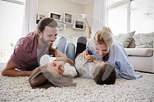Parents Tickling Children As They Play Game In Lounge Together