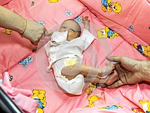 Parents touch her newborn child at the crib