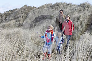 Parents with two children (3-6) walking in long grass