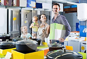 parents with two kids choosing kitchenware in home appliance store