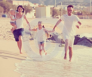 Parents with two kids jogging on beach