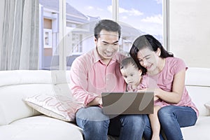 Parents using a laptop with their daughter