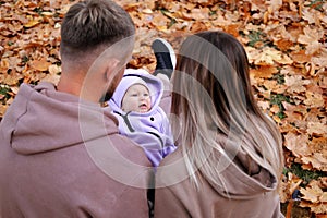 Parents on a walk with a baby in the autumn park. The baby is crying and naughty